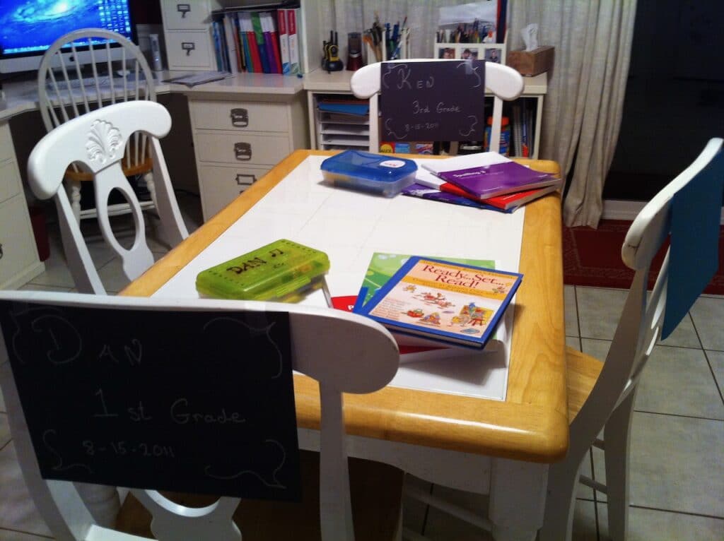 Photo of white dining table with school books on top of it.