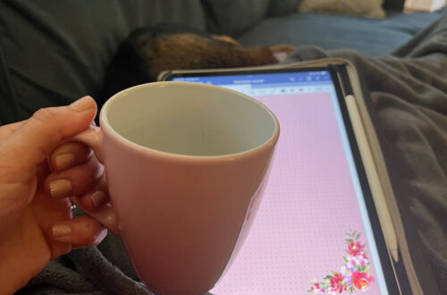 Hand holding pink coffee cup with iPad screen in background. Escape from routine prison