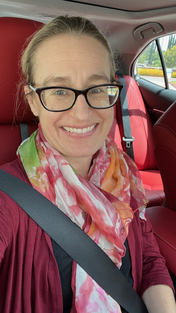 Photo of author in car with a pink floral scarf on.