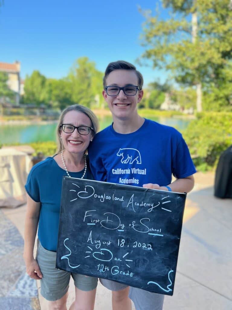 Author and Son outside holding a sign that describes the first day of school