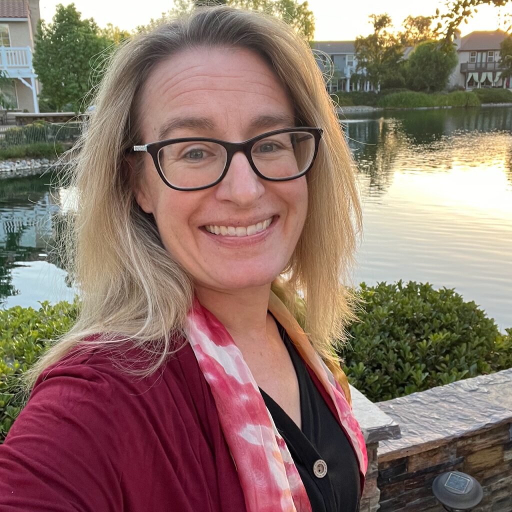 Author taking a selfie outside with burgundy cardigan, floral scarf, and black shirt.