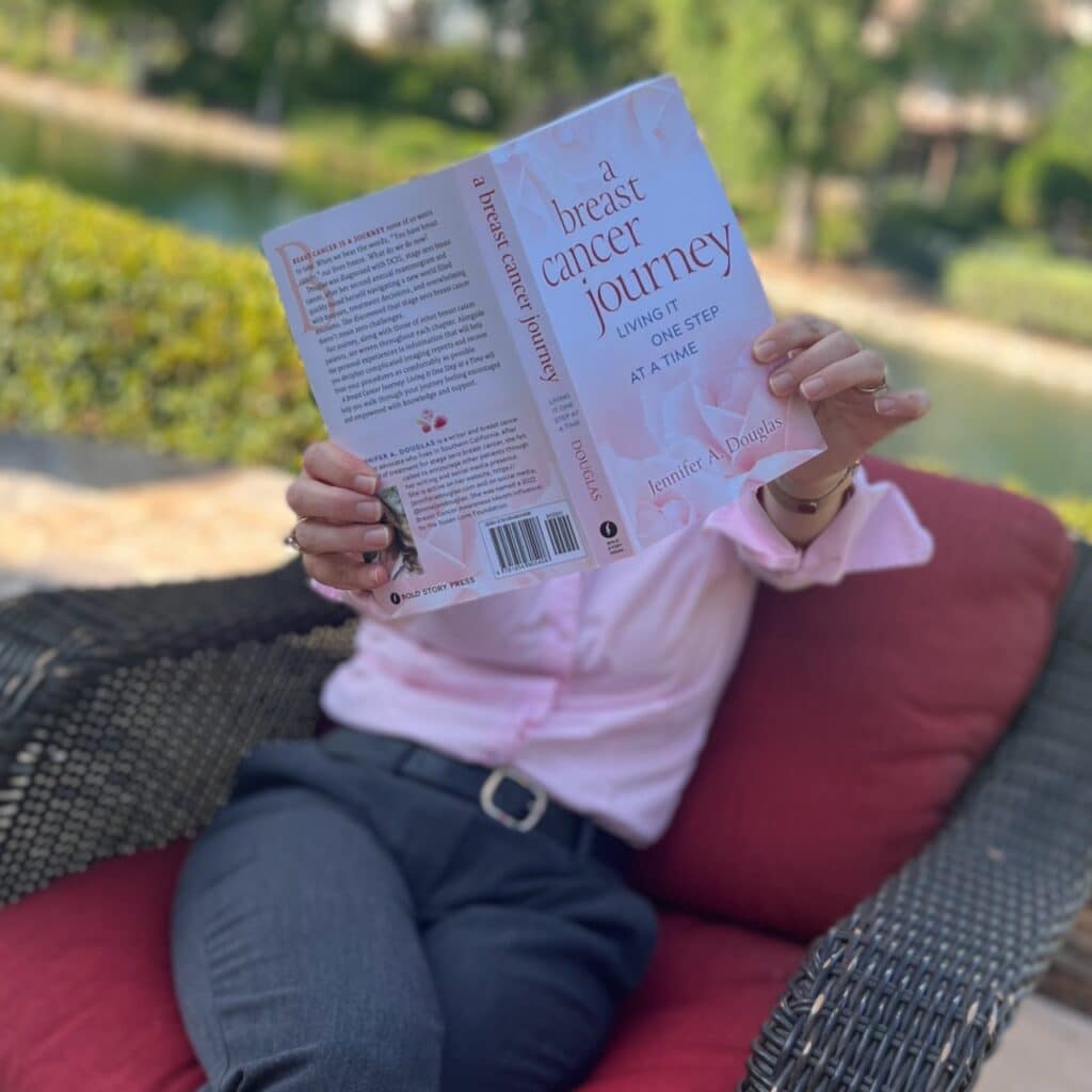 Author holding copy of A Breast Cancer journey book out to the camera