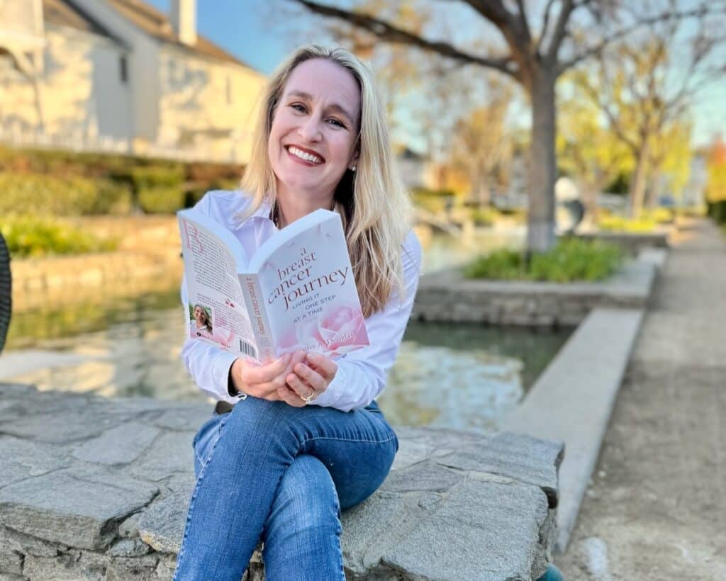 Jennifer A Douglas author seated with a copy of her book A Breast Cancer Journey: LIving It One Step at a Time