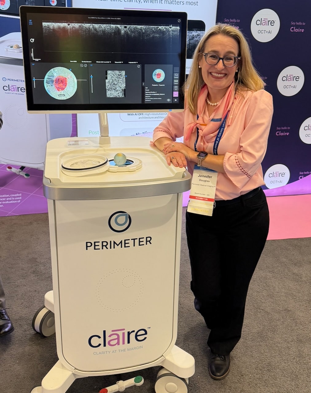 Jennifer Douglas standing next to the Perimeter Claire Machine wearing a pink shirt